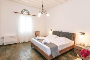 a bedroom with a large white bed and a window at Windmill Villa in Tinos in Agios Sostis