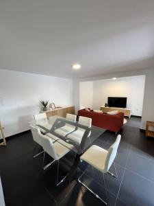 a living room with a glass table and white chairs at Ribeira Roots Residence in Santa Cruz