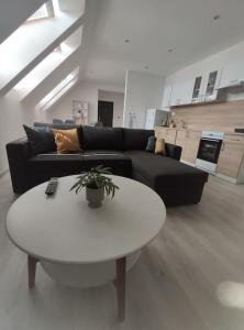 a living room with a black couch and a white table at Krásny nový prízemný apartmán in Nové Zámky