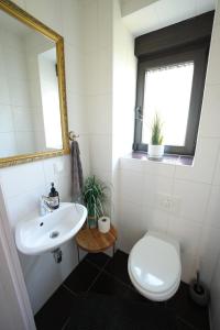 ein Badezimmer mit Waschbecken und Toilette und einem Fenster in der Unterkunft Ferienhaus in Brandenburg an der Havel in Brandenburg an der Havel + 8 Fotos