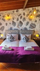 a bedroom with two beds and a stone wall at Los Cerrajones: spectacular views from the cliff in Agulo
