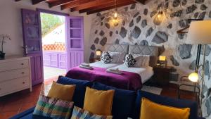 a bedroom with a bed and a stone wall at Los Cerrajones: spectacular views from the cliff in Agulo