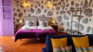 a bedroom with a bed with a purple bedspread at Los Cerrajones: spectacular views from the cliff in Agulo
