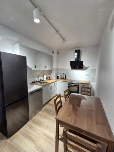 - une cuisine avec une table en bois et un réfrigérateur noir dans l'établissement Apartament Sportowa przy SUNTAGO DEEPSPOT Mszczonów, à Mszczonów