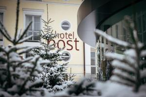 a snow covered tree in front of a hotel sign at HOTEL POST alpine cityflair in Brunico