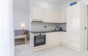 a kitchen with white cabinets and a couch at Apartments Funtana with pool in Funtana