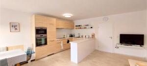 a kitchen with wooden cabinets and a tv in it at Byt na náměstí in Nejdek