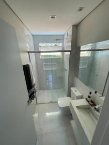 a white bathroom with a shower and a toilet at Casa em Santo Hilário - MG in Guapé