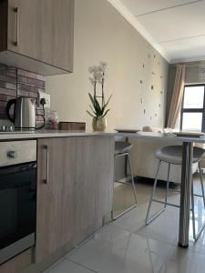 a kitchen with a counter and a table and chairs at Classy 2 bedroom in Halfway Gardens in Midrand +29 photos