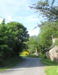 una strada tortuosa con un edificio in pietra e alberi di Rainbow Cottages a Saint-Nicolas-du-Pélem