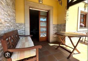 a porch with a bench and a table and a door at Chalet adosado en Ribadesella in Ribadesella