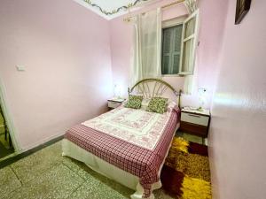 a small pink bedroom with a bed and a window at La casita de Larache in Larache +2 photos