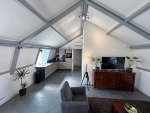 a living room with a couch and a tv at Appartement Warmond in Warmond