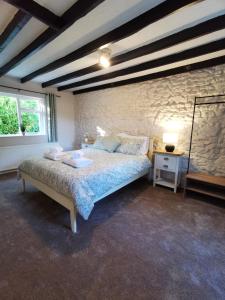 a bedroom with a bed and a stone wall at Plasbach Cottage in Llandeilo