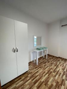 a white room with a table and a cabinet at Nikolla's apartment in Himare