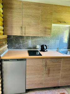 a kitchen with wooden cabinets and a sink at Dolce vita cottage - waterfront in Bihać