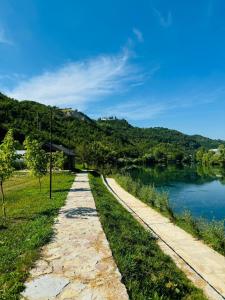 a path next to a river with a mountain at Dolce vita cottage - waterfront in Bihać +8 photos