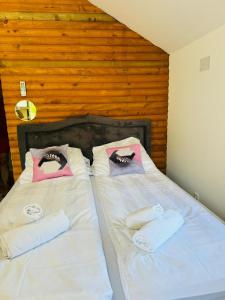 a bedroom with two beds with white sheets and pink pillows at Dolce vita cottage - waterfront in Bihać