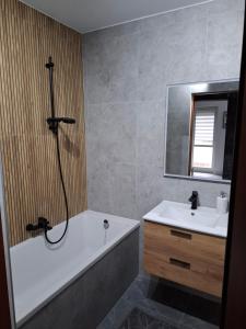 a bathroom with a bath tub and a sink and a mirror at Przytulny 2-pokojowy apartament na wakacje w Gdańsku in Gdańsk