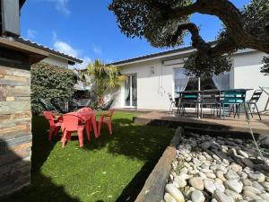 a yard with a table and chairs in front of a house at Spa, Climatisation, Piscine chauffée, Pétanque et Calme au Bassin d'Arcachon in Le Teich