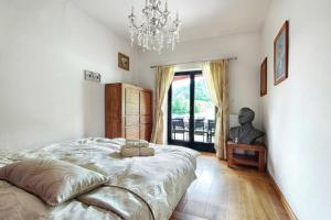 a bedroom with a large bed and a chandelier at Villa Noiram - Your dream Getaway in Nature in Senožeče +16 photos