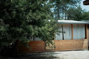 a wooden building with a fence and a tree at Каравана GYPSY in Chernomorets