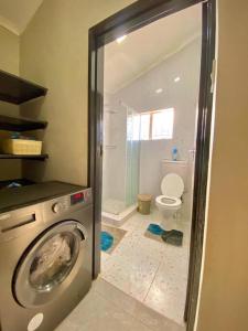 a bathroom with a washing machine and a toilet at Down Town Delight - 2BR Budget Retreat in Gaborone