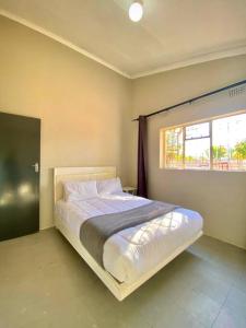 a bed in a bedroom with a window at Down Town Delight - 2BR Budget Retreat in Gaborone