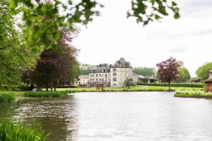 a view of a large house from across a lake at Hébergement au château 104 in Tinlot
