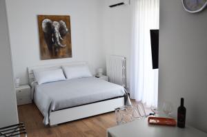 a white bedroom with a bed and a painting on the wall at Marimar Apartment in Bari