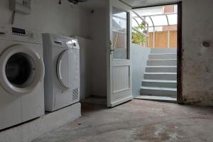 a laundry room with a washing machine and a staircase at Lejlighed nær Billund med gratis parkering og terrasse med grill in Grindsted
