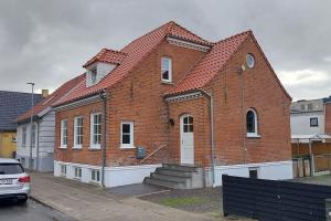 a large brick building with a red roof at Lejlighed nær Billund med gratis parkering og terrasse med grill in Grindsted