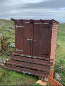 a wooden outhouse sitting on top of a field at Eco Crofter's Wagon by the Sea - Off Grid Experience - No electricity - As seen soon on Netflix in Oldshoremore