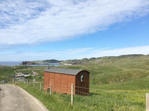 a smallshed on a hill next to a road at Eco Crofter's Wagon by the Sea - Off Grid Experience - No electricity - As seen soon on Netflix in Oldshoremore