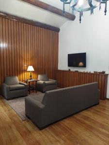 a living room with a couch and a flat screen tv at Huluan Alto da Boa Vista in Campos do Jordão