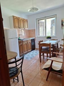 ロクヴァ・ロゴズニツァにあるOliva Apartmentsのキッチン(テーブル、椅子、白い冷蔵庫付)