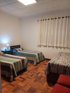 a room with two beds and a red chair at Huluan Alto da Boa Vista in Campos do Jordão