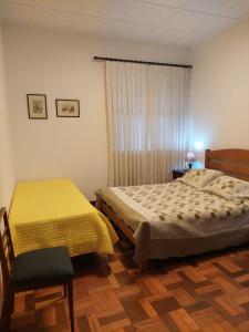 a bedroom with a bed and a chair and a window at Huluan Alto da Boa Vista in Campos do Jordão