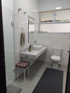 a white bathroom with a sink and a toilet at Huluan Alto da Boa Vista in Campos do Jordão