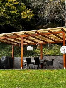 a wooden pergola with a table and chairs under it at Liz Mari Apartments near Terme Olimia in Podčetrtek