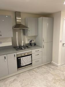 a kitchen with white cabinets and a stove top oven at Mesnes Place in Wigan +24 photos