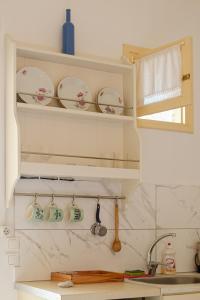 a kitchen with white shelves with dishes and a sink at ASTYSTUDIO in Astypalaia Town