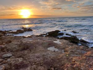 a sunset over the ocean with rocks in the water at Casa Vacanze A CASUZZA in Marsala