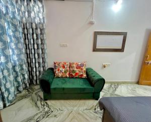 een groene bank in een kamer met een raam bij The Cozy Nook in Udaipur