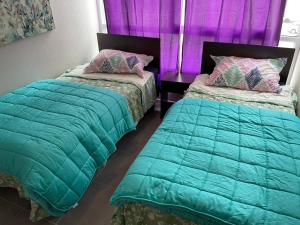2 camas en una habitación con cortinas moradas en Departamento Alto Serena V, en La Serena