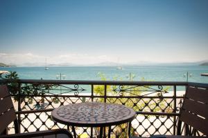 a table and chairs on a balcony overlooking the water at SeaFront Stone Suites in Vonitsa