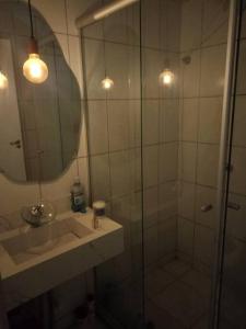 ein Badezimmer mit Dusche, Waschbecken und Spiegel in der Unterkunft Apartamento central em Contagem in Contagem