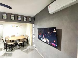 a dining room with a table and a tv on a wall at Casa Ubatubana I, em Praia do Sapê - Ar condicionado, garagem, cozinha completa e Wi-Fi in Ubatuba