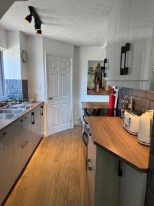 a kitchen with white cabinets and a wooden floor at Luxury Jacuzzi Fast WIFI PS5 Gym Parking 2 spaces in Hereford