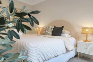 オーシャン・グローブにあるMadeley Family Getaway- Sleeping 8, central, aircon, close to shops, beach, parks, spaciousの白いベッドと植物が備わるベッドルーム1室が備わります。